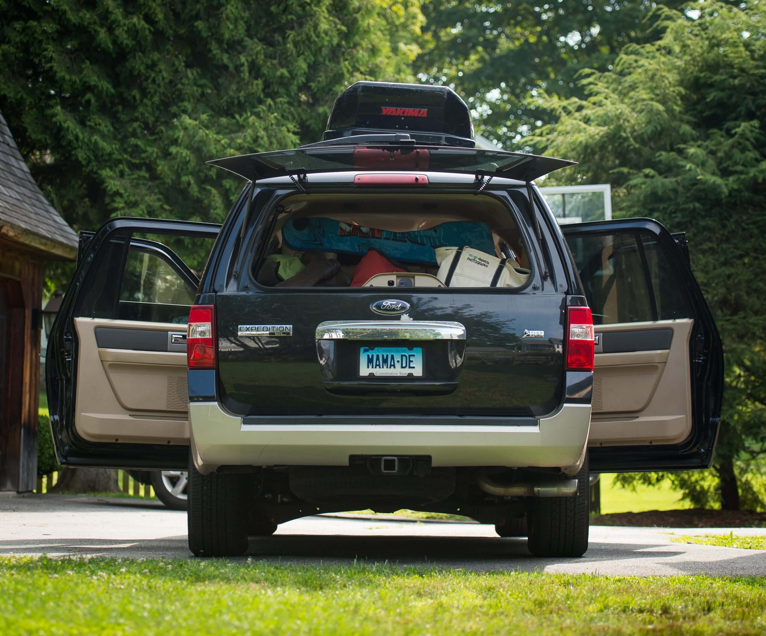 A parked Ford Explorer is packed with items and all four doors are open.
