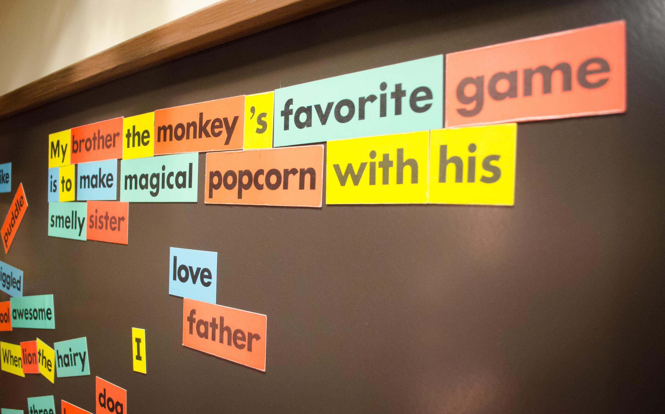 Magnetic words are placed on a board. The words read "My brother the monkey's favorite game is to make magical popcorn with his smelly sister."
