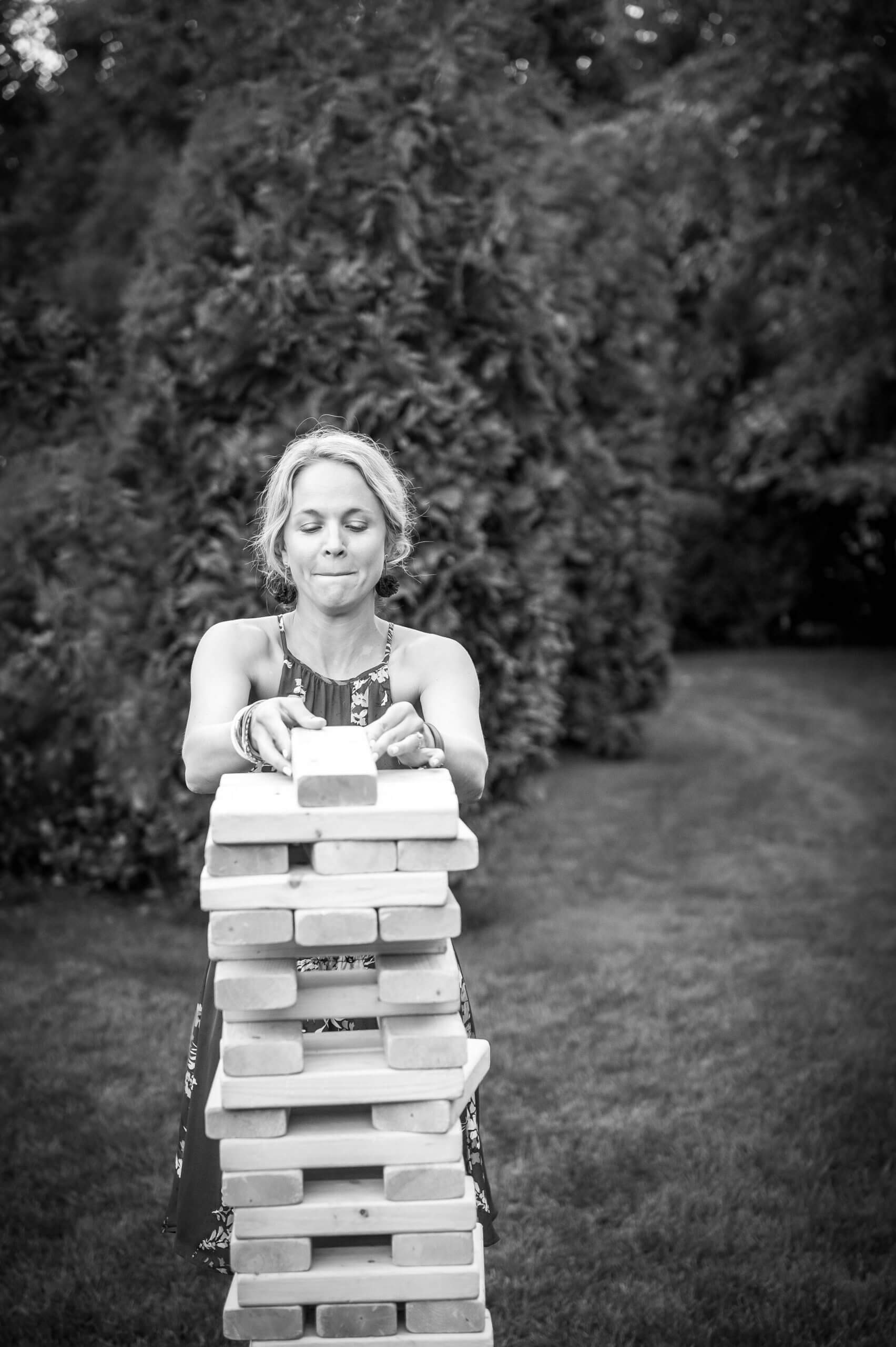 A woman plays lawn Jenga, carefully placing a piece on the top of the tower.