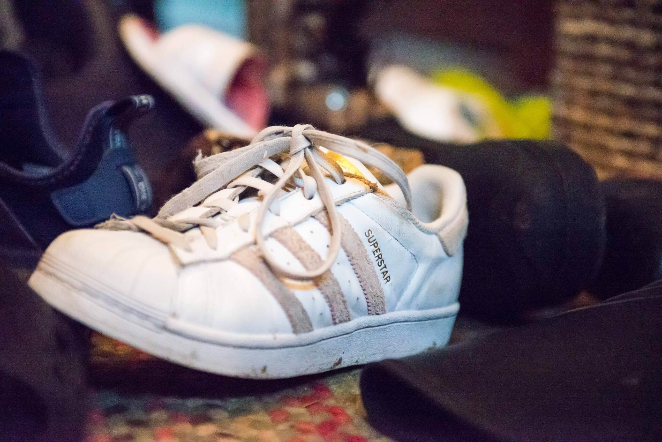 A focused view of a tennis shoe in front of an unfocused view of other shoes.