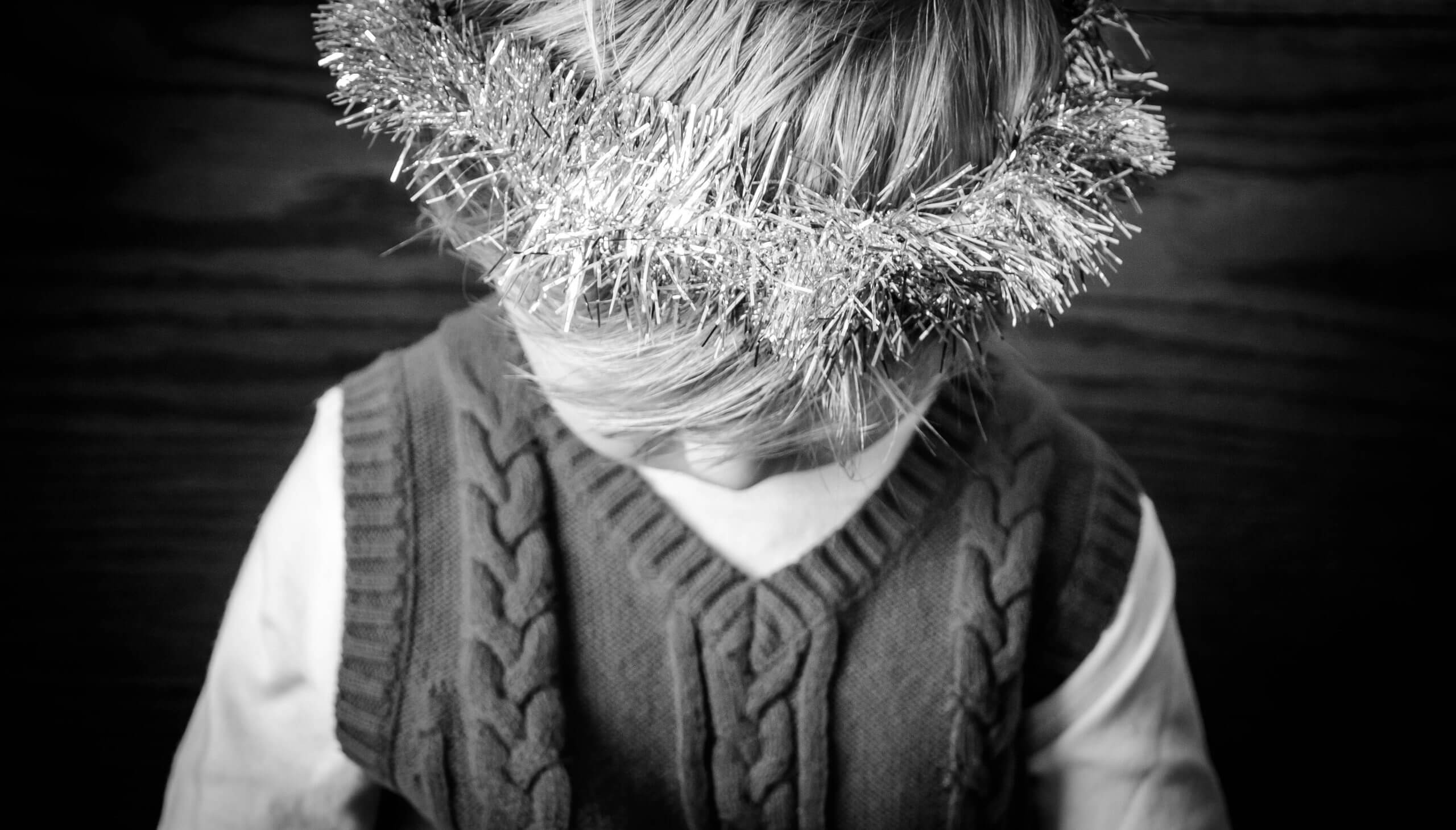 An overhead view of a child with a tinsel ring worn on the crown of his head.