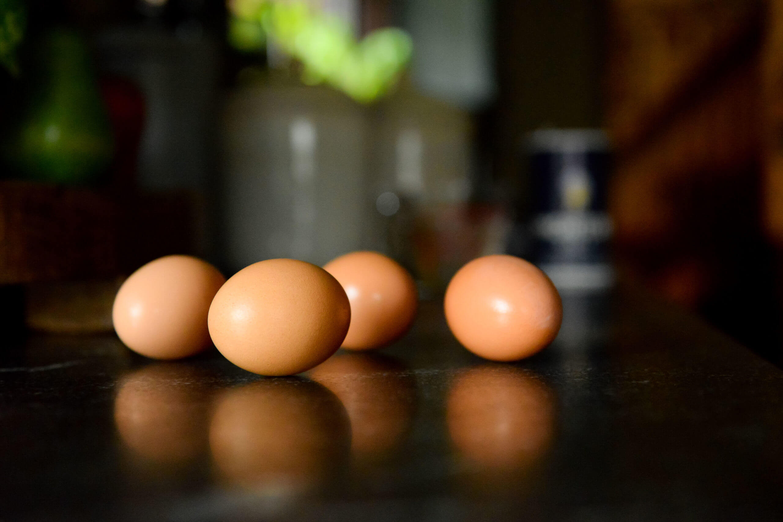 Four eggs on a table. The reflection of the eggs is visible on the table.