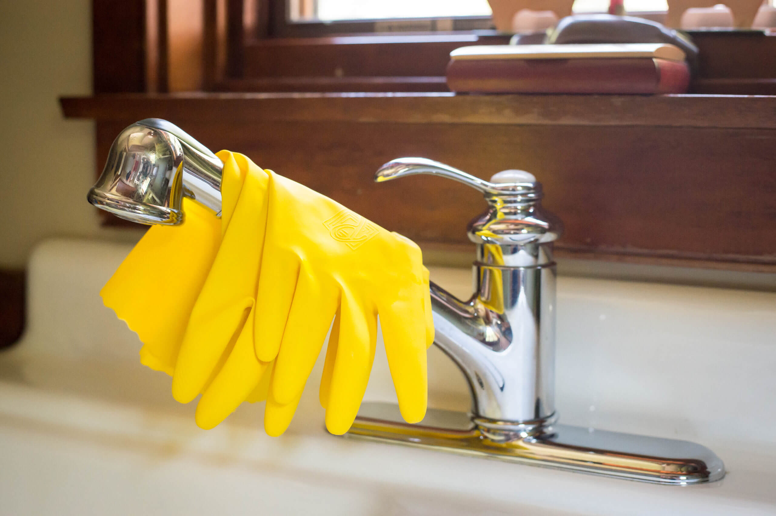 Cleaning gloves are folded over the faucet of a kitchen sink.