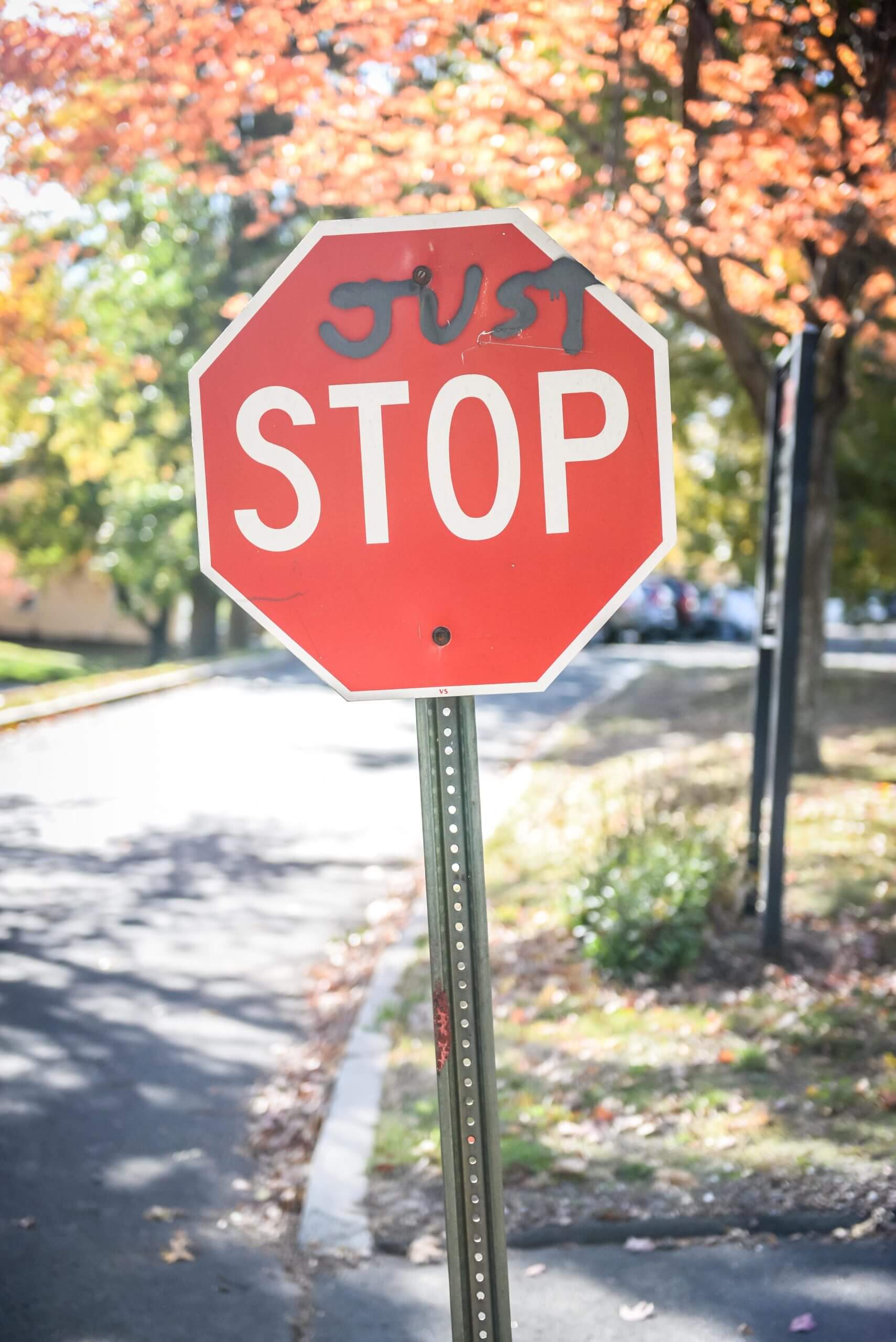 A stop sign reads "just stop." The word "just" is written in spray painted letters above "stop."