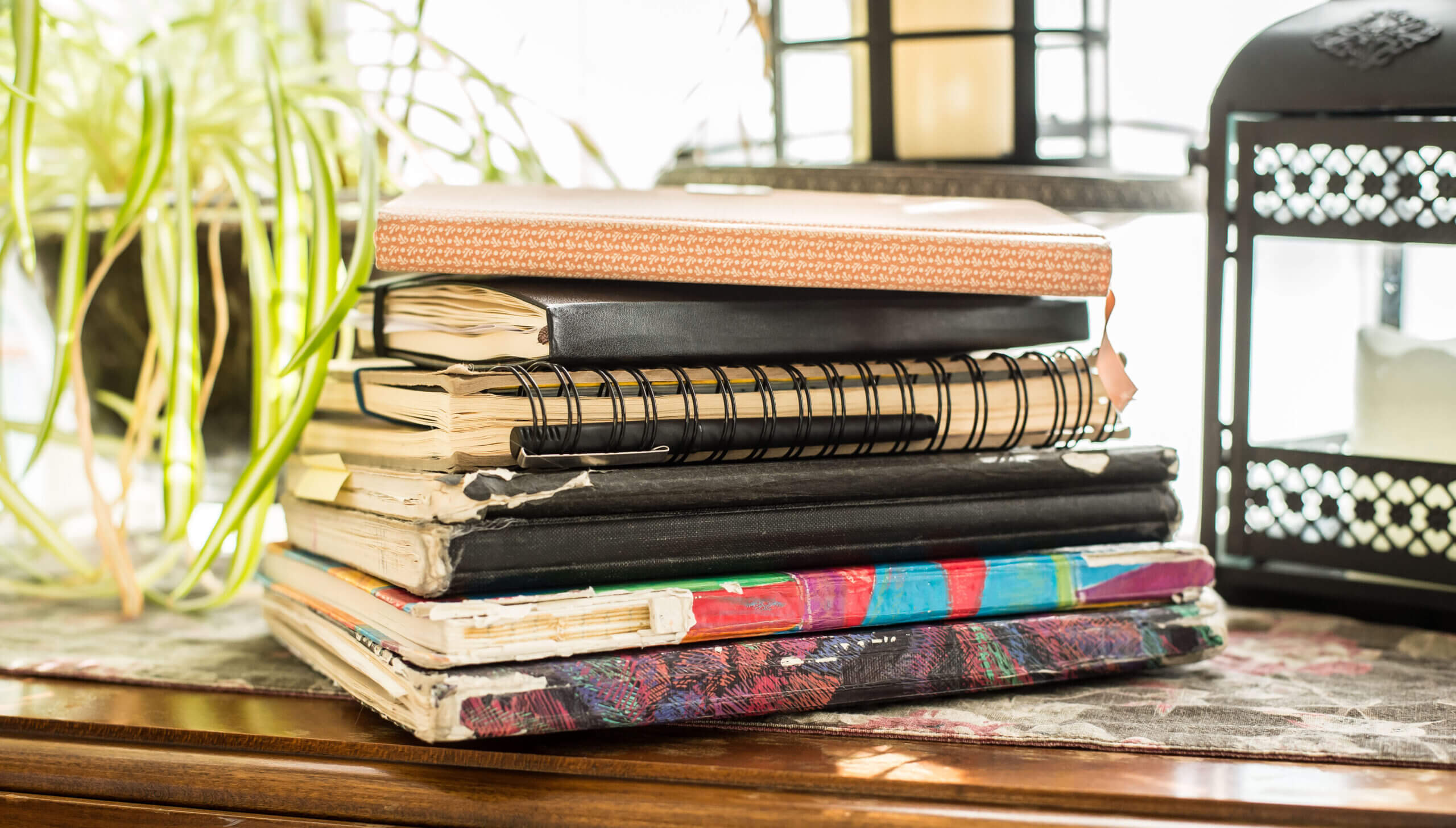 A stack of journals on a table, all different sizes and shapes.