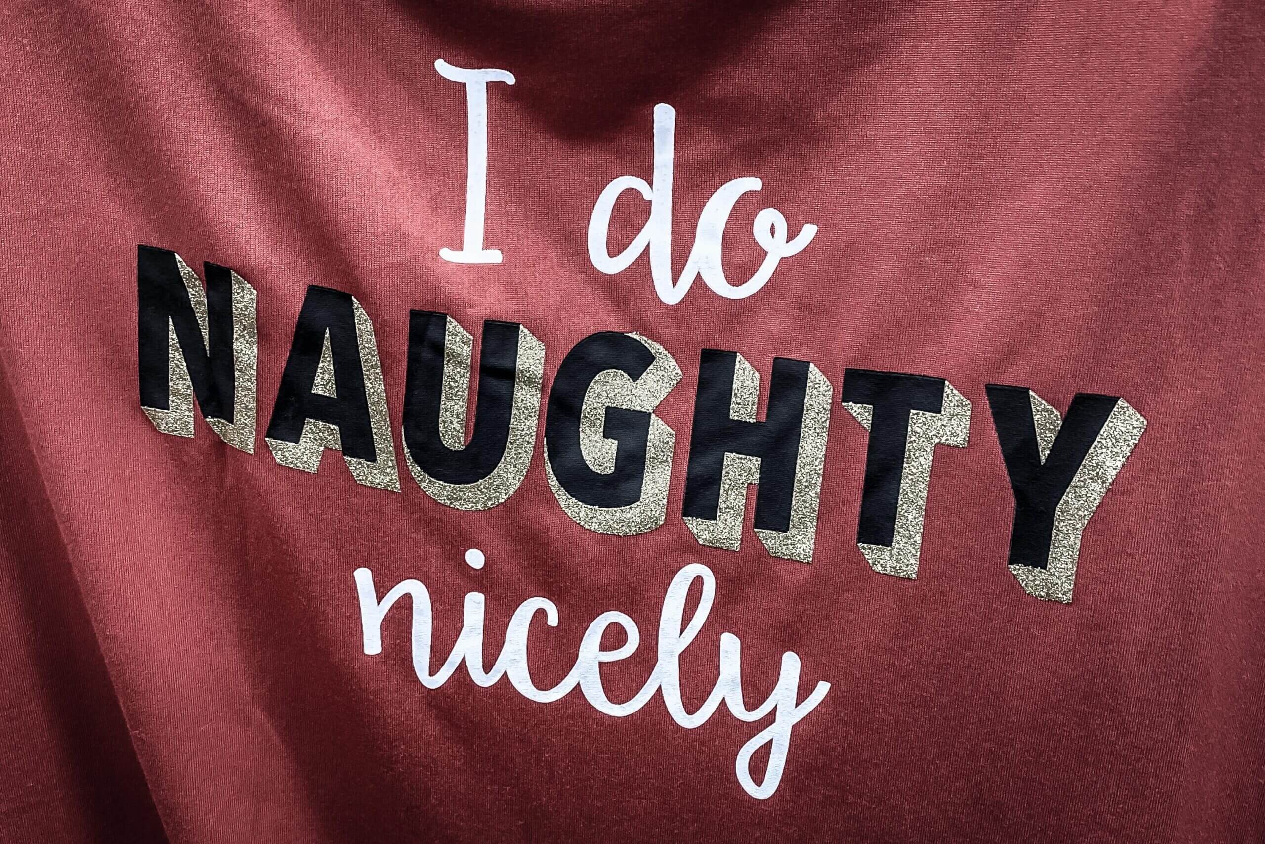 A tee shirt with cursive text reads as follows. I do naughty nicely.