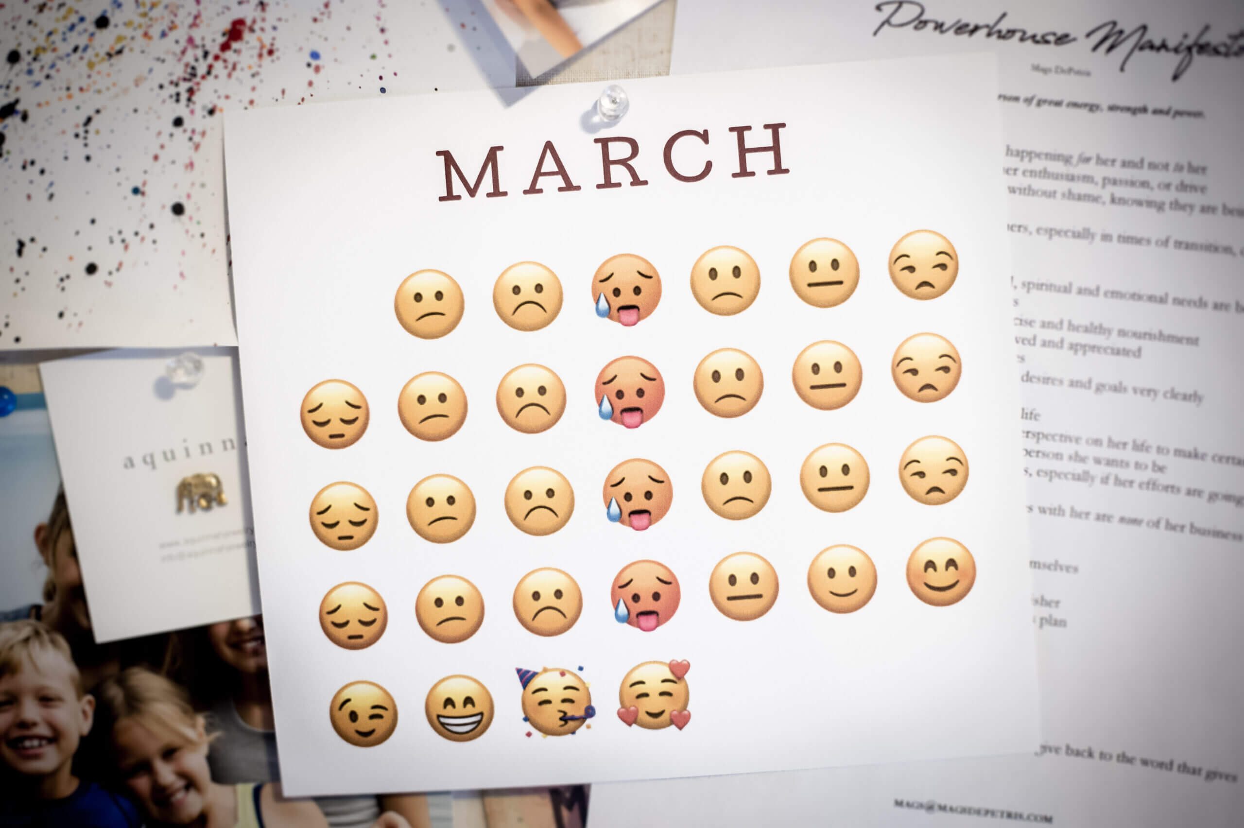 A March calendar on a cork board with emojis instead of numbers. All the emojis are sad or grumpy and begin to change to happy emojis at the end of the month.