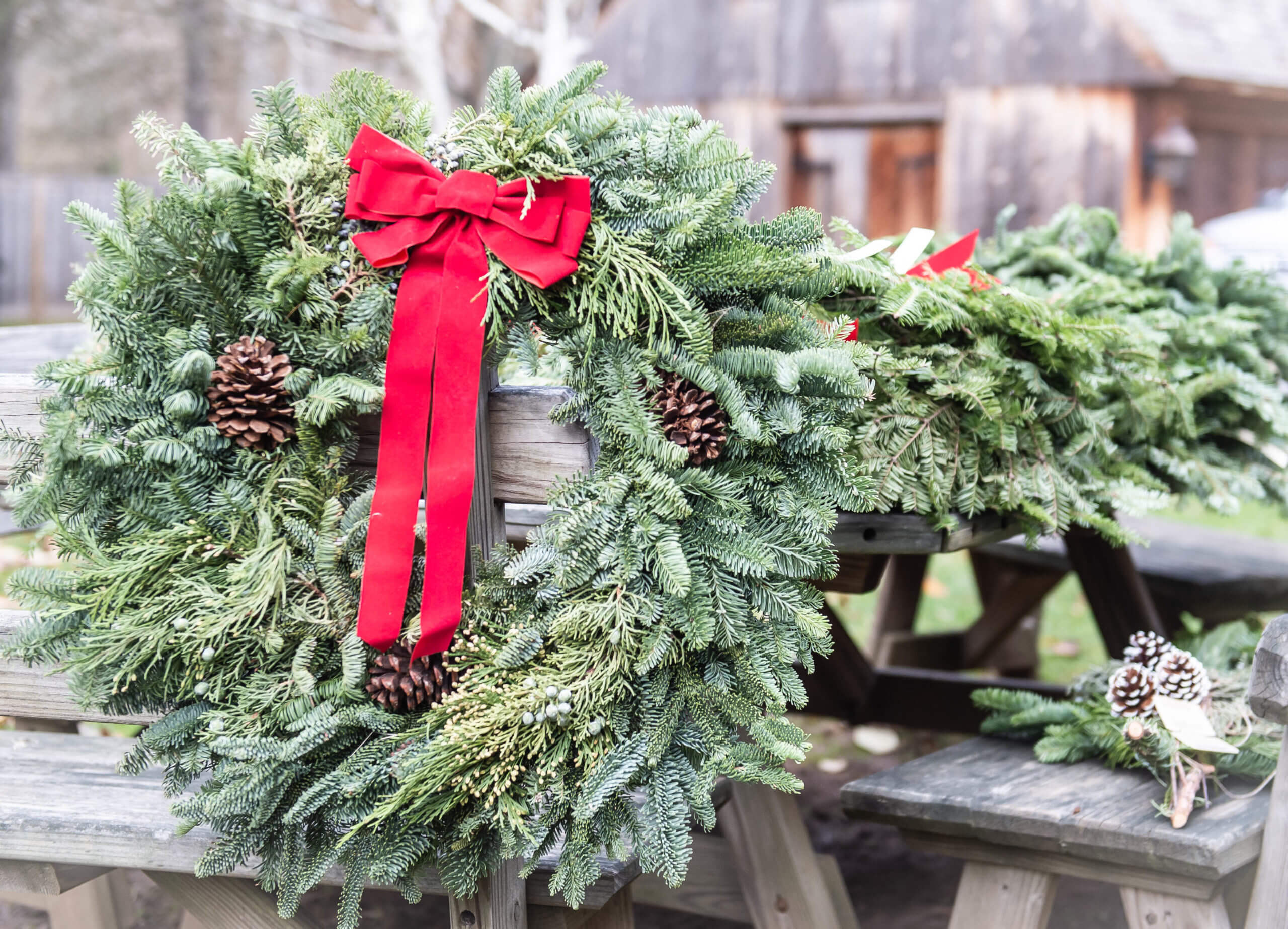 Christmas wreath hanging on the back of a wooden bench.