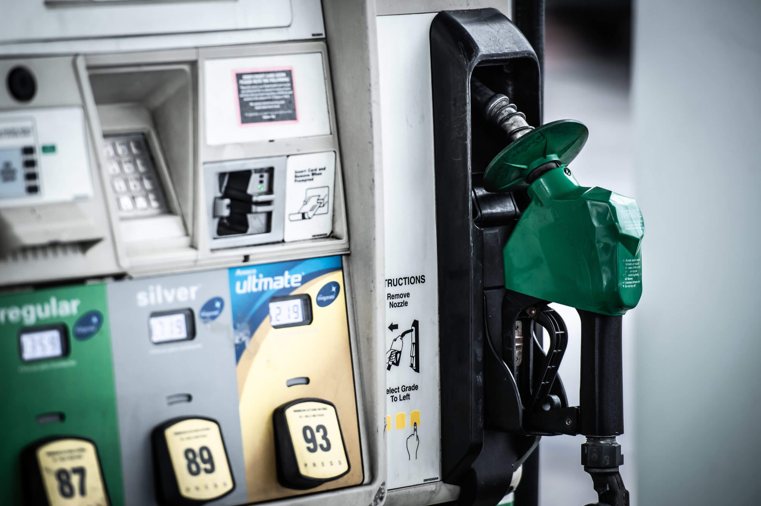 Color image of a green-handled hose in a gas pump at a gas station.