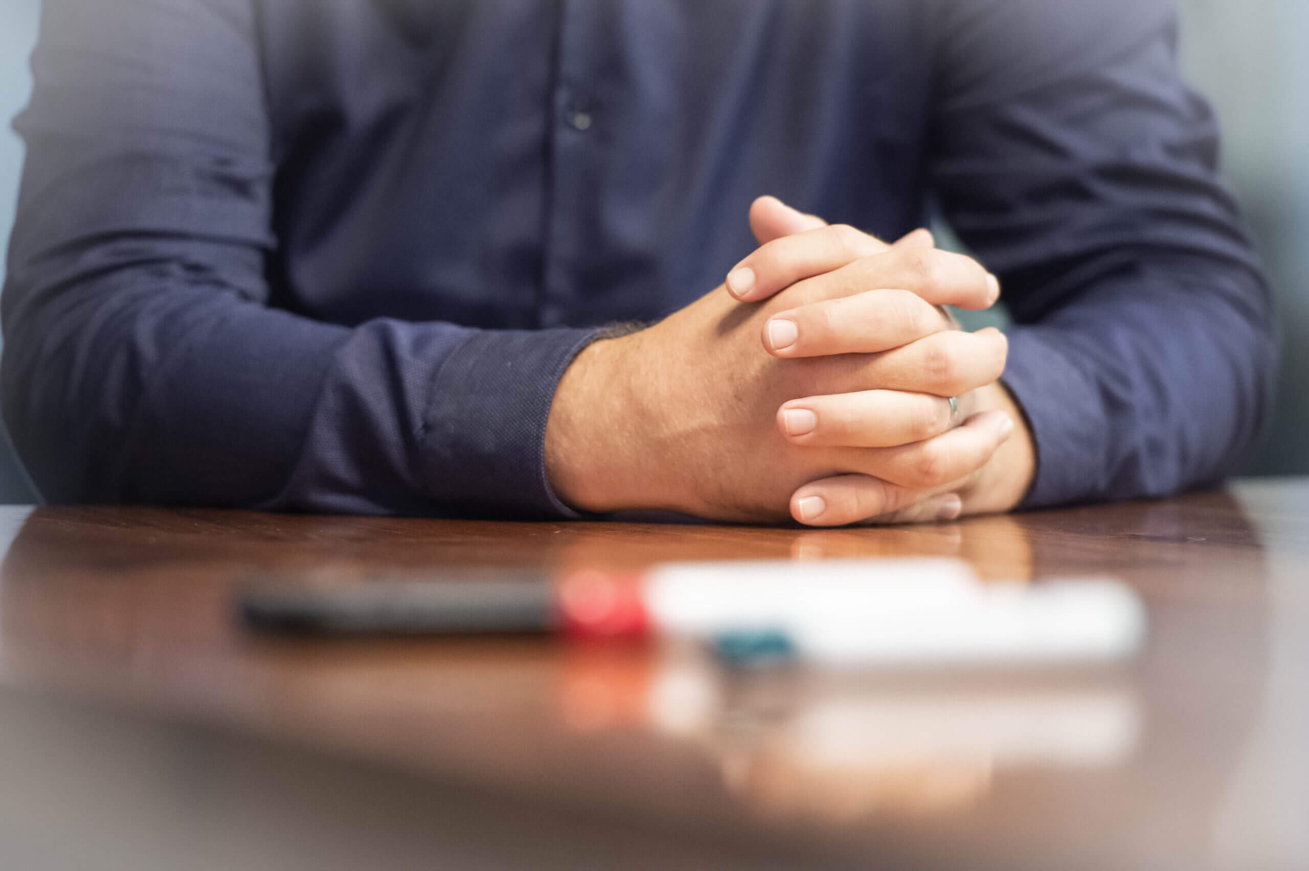 Color image of a man's hands on a conference room table.