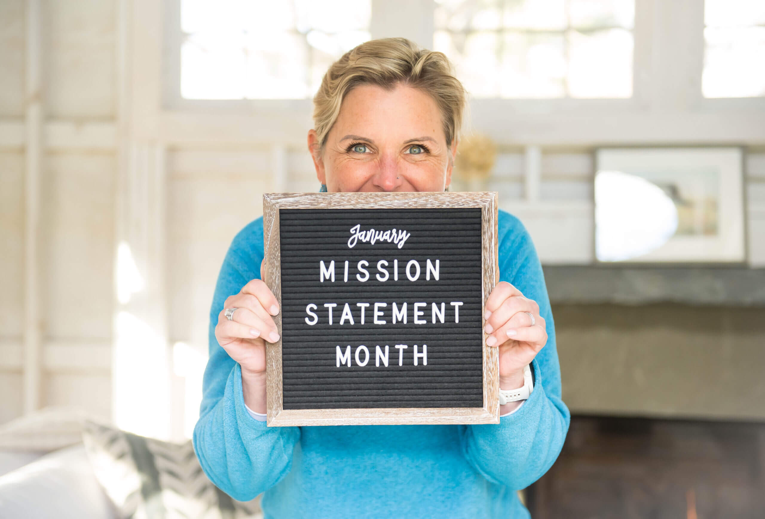 Mags smile is hiding behind a sign that reads January Mission Statement Month