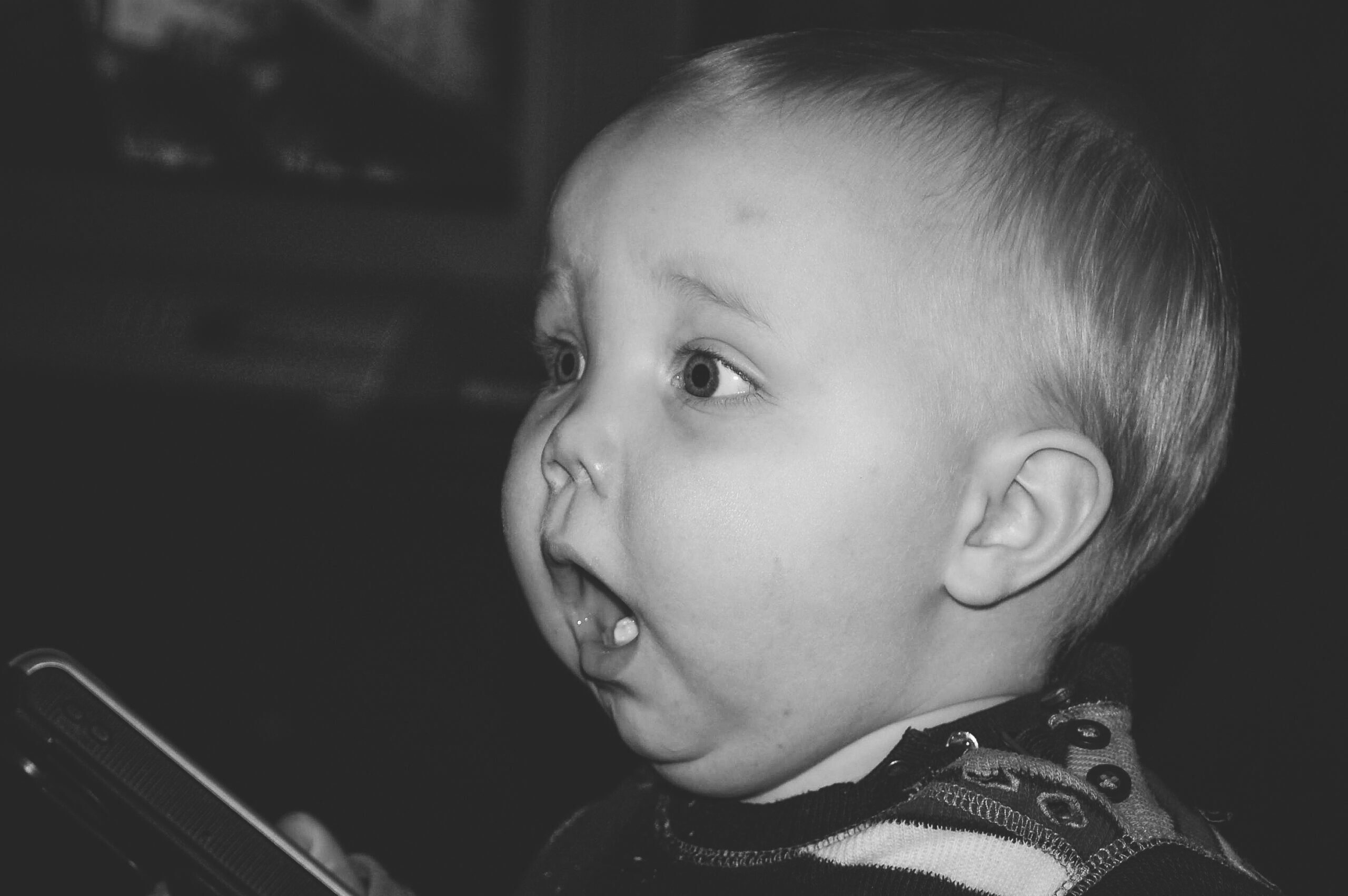 Black and white image of a chubby white toddler with a surprised look on his face.