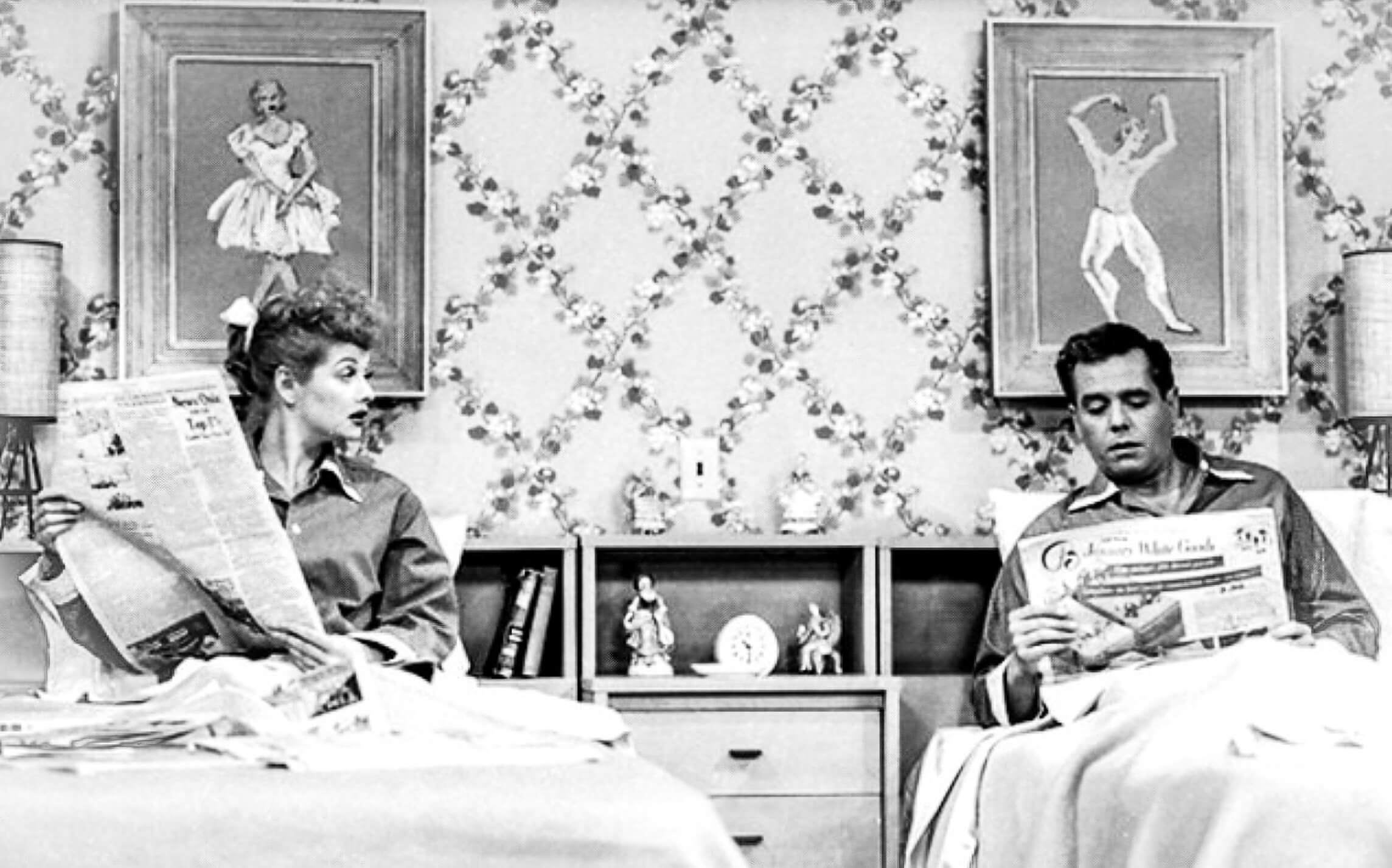 Black and white image of Lucille Ball and Desi Arnaz reading the papers in separate beds.