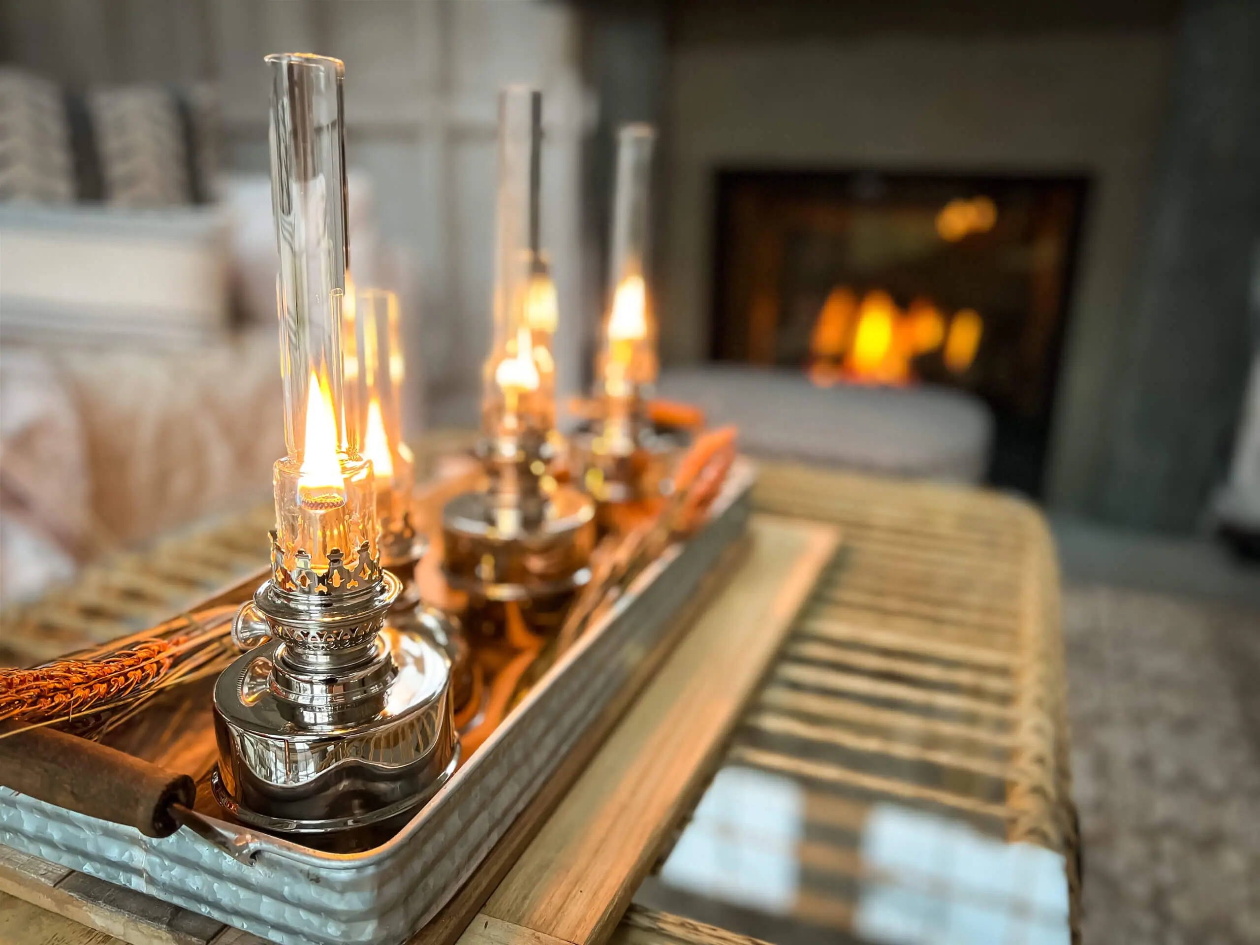 Color image of five oil lamps burning with a fireplace burning in the background