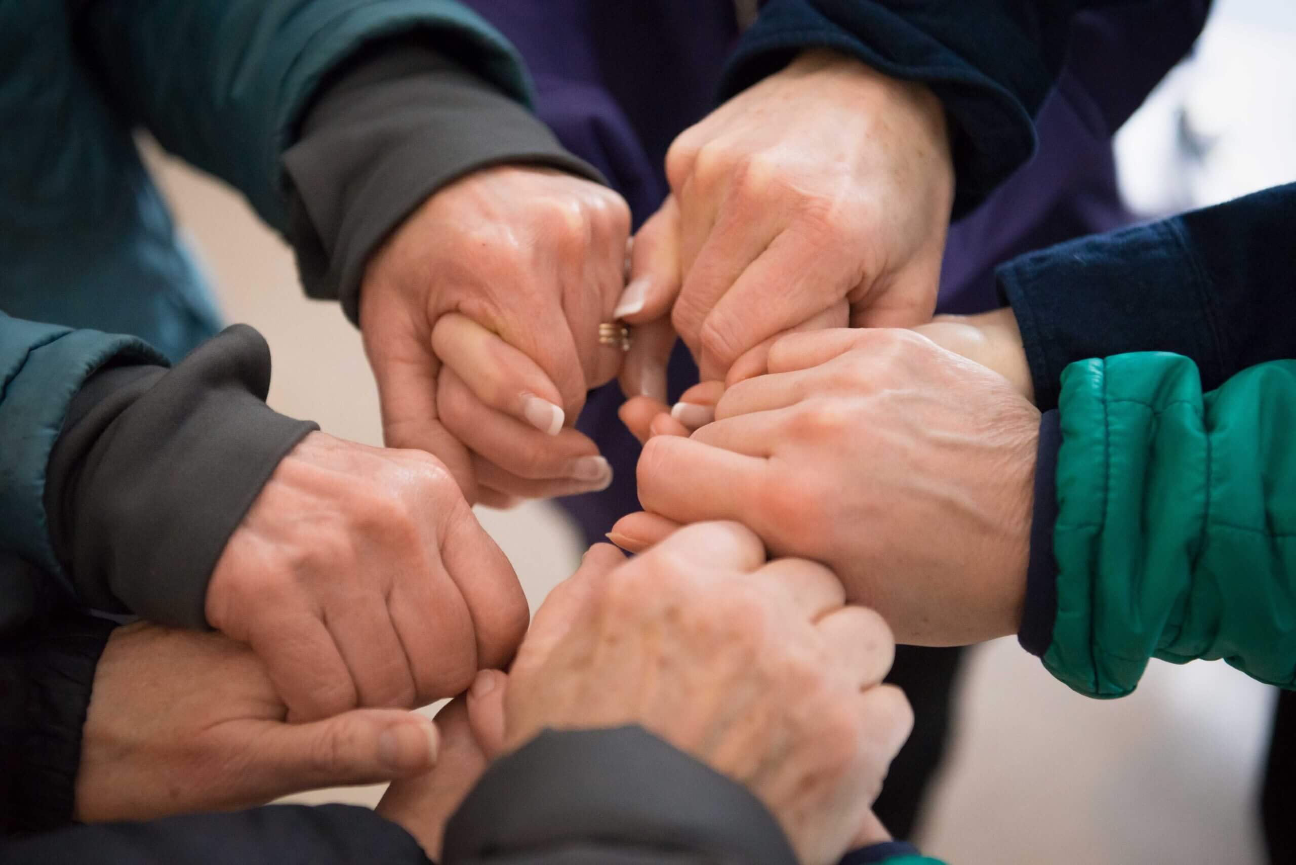 Photo from above of a circle of white women holding hands.