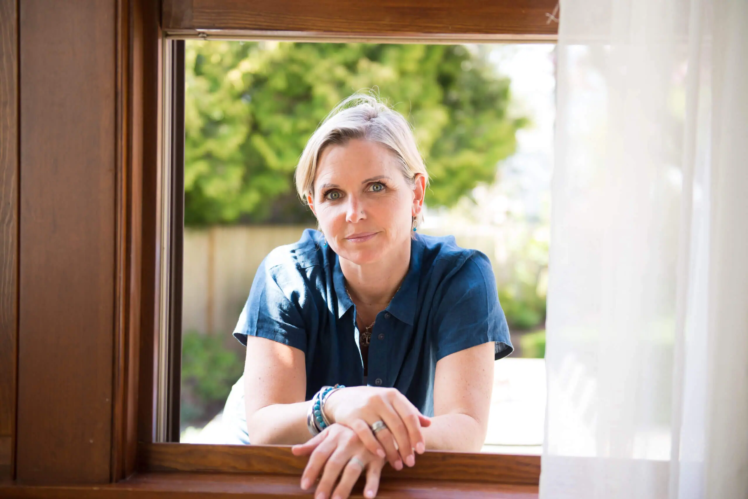 White middle aged woman in the frame of a window.