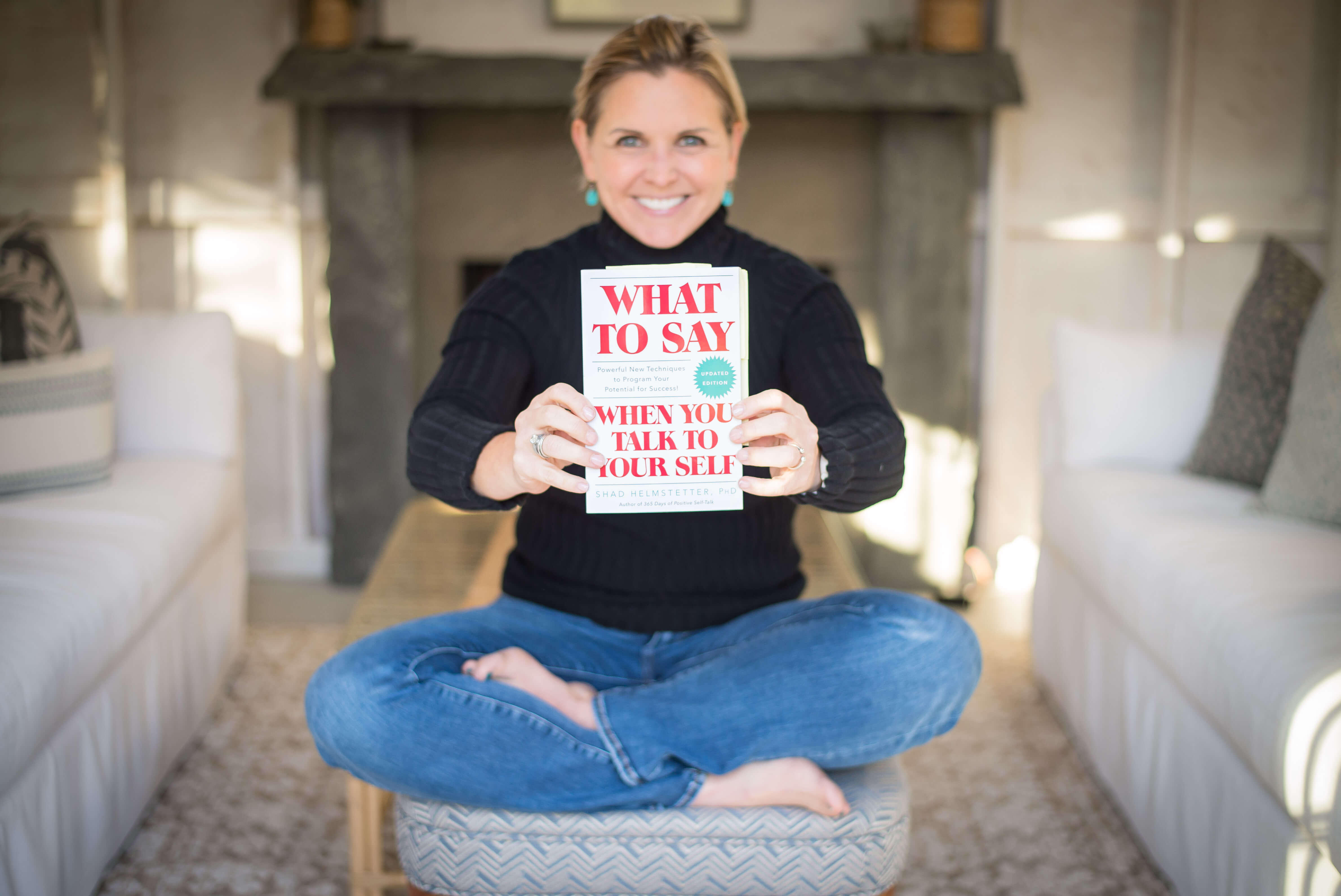 Image of a white middle aged woman holding the book: What to Say When You Talk to Yourself by Shad Helmstetter.