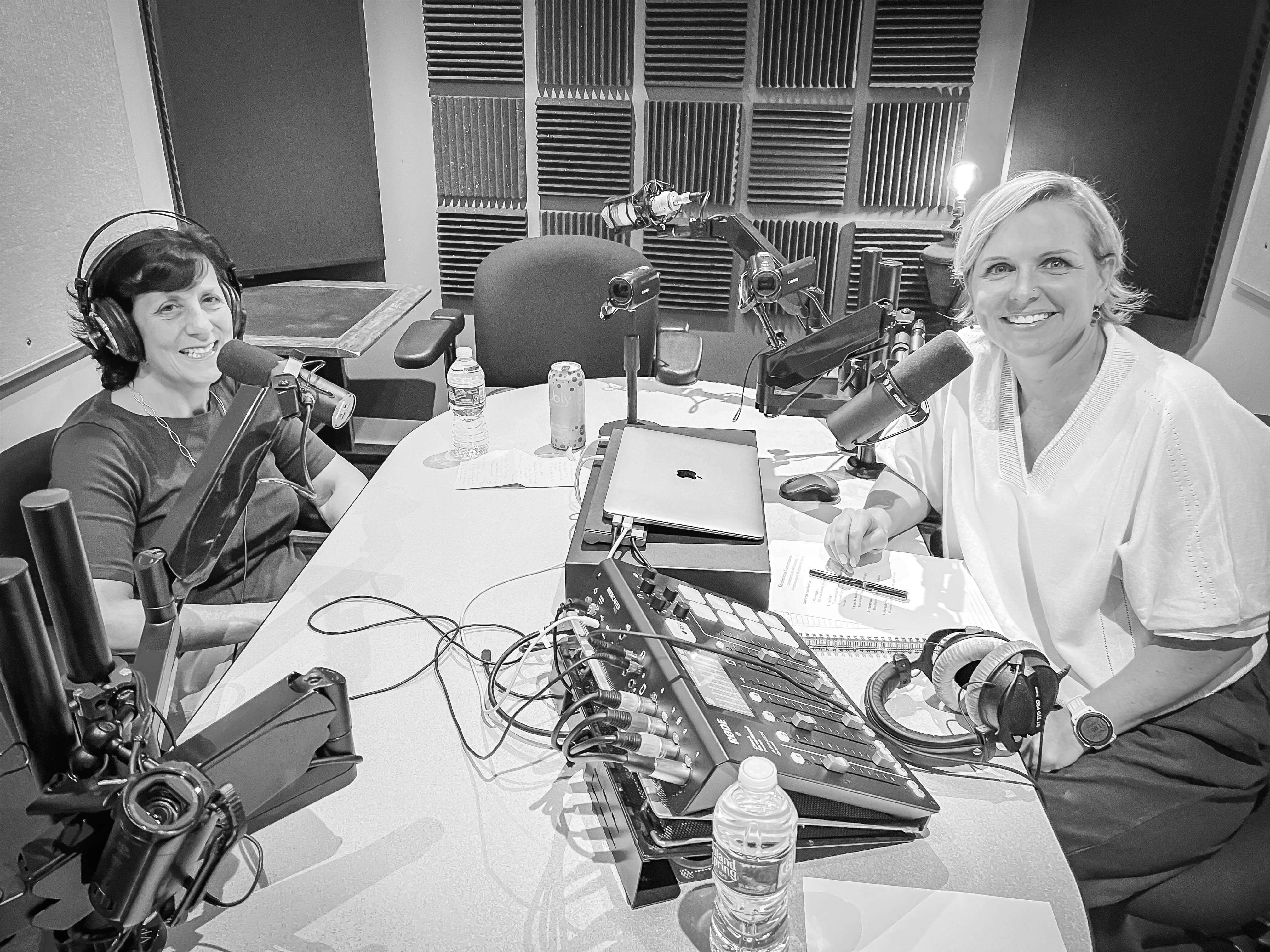 Black and white image of two middle aged white women in a podcast recording studio.