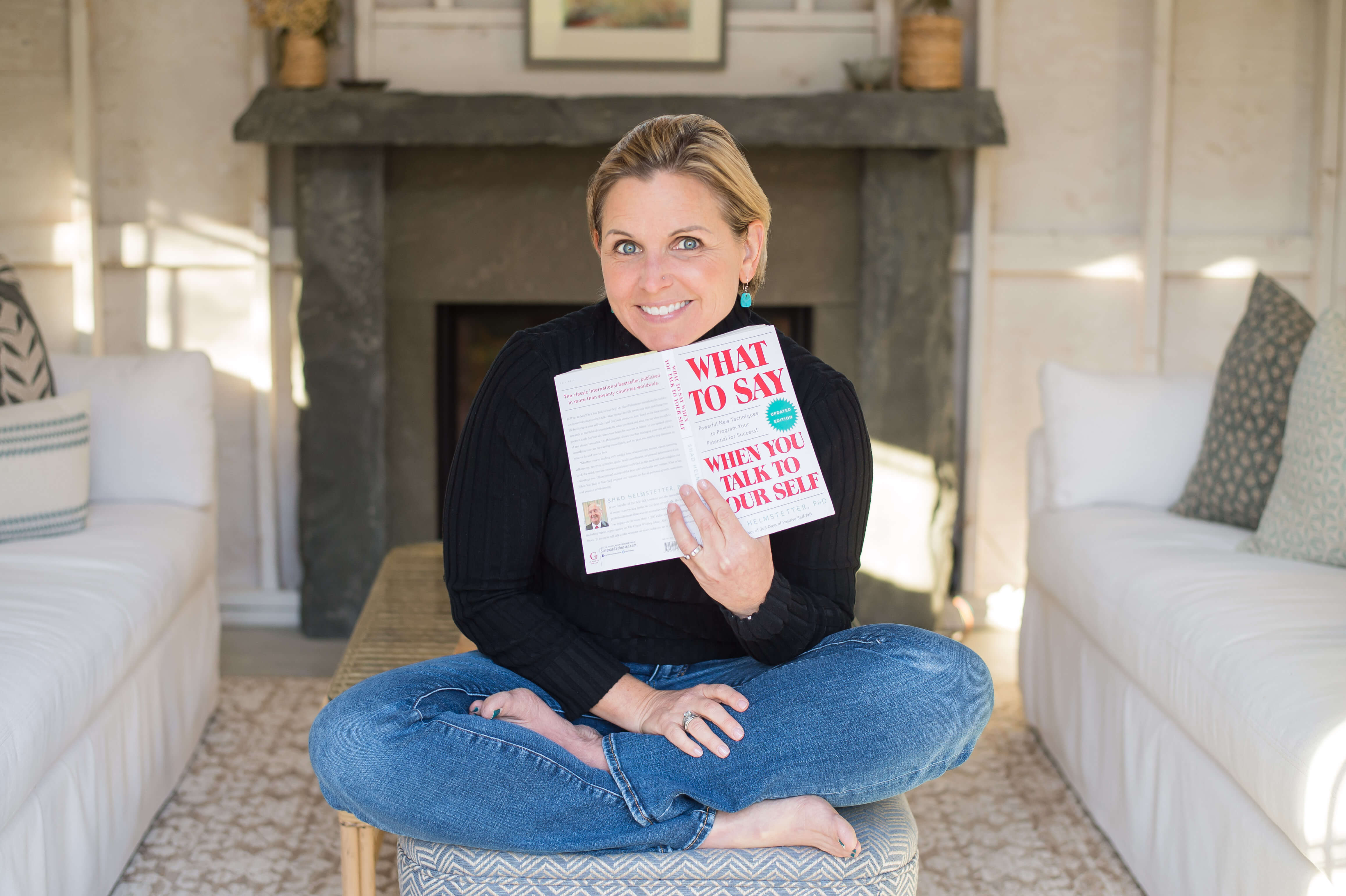White middle aged woman holding the book What To Say When You Talk to Yourself.