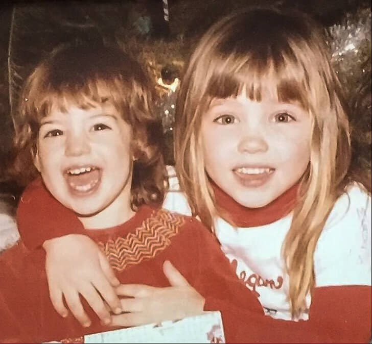 Two little white girls smiling in a color photo taken at Christmas in 1980.
