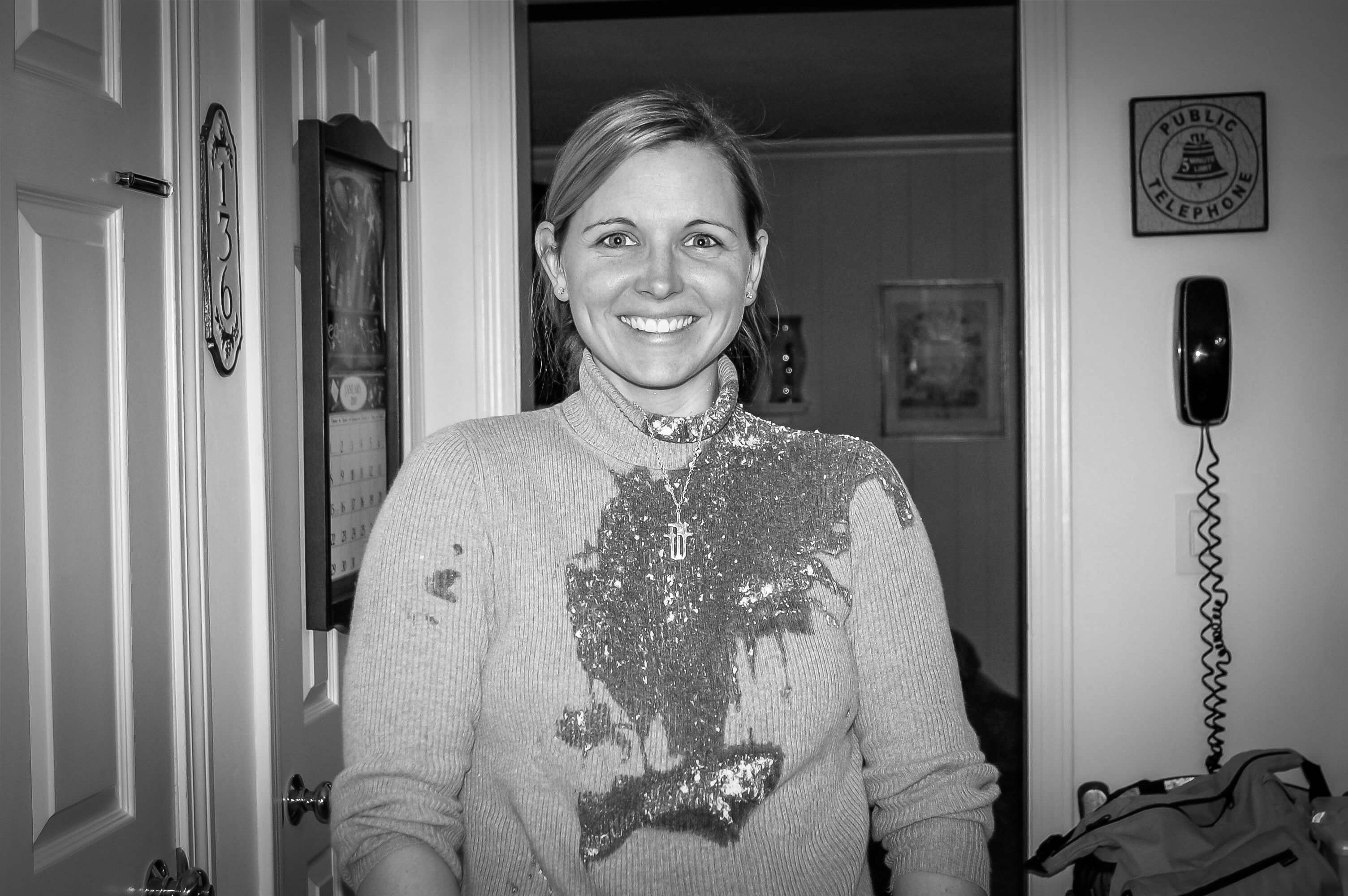 Black and white photo of smiling thirty-something mom with vomit all over her turtleneck.