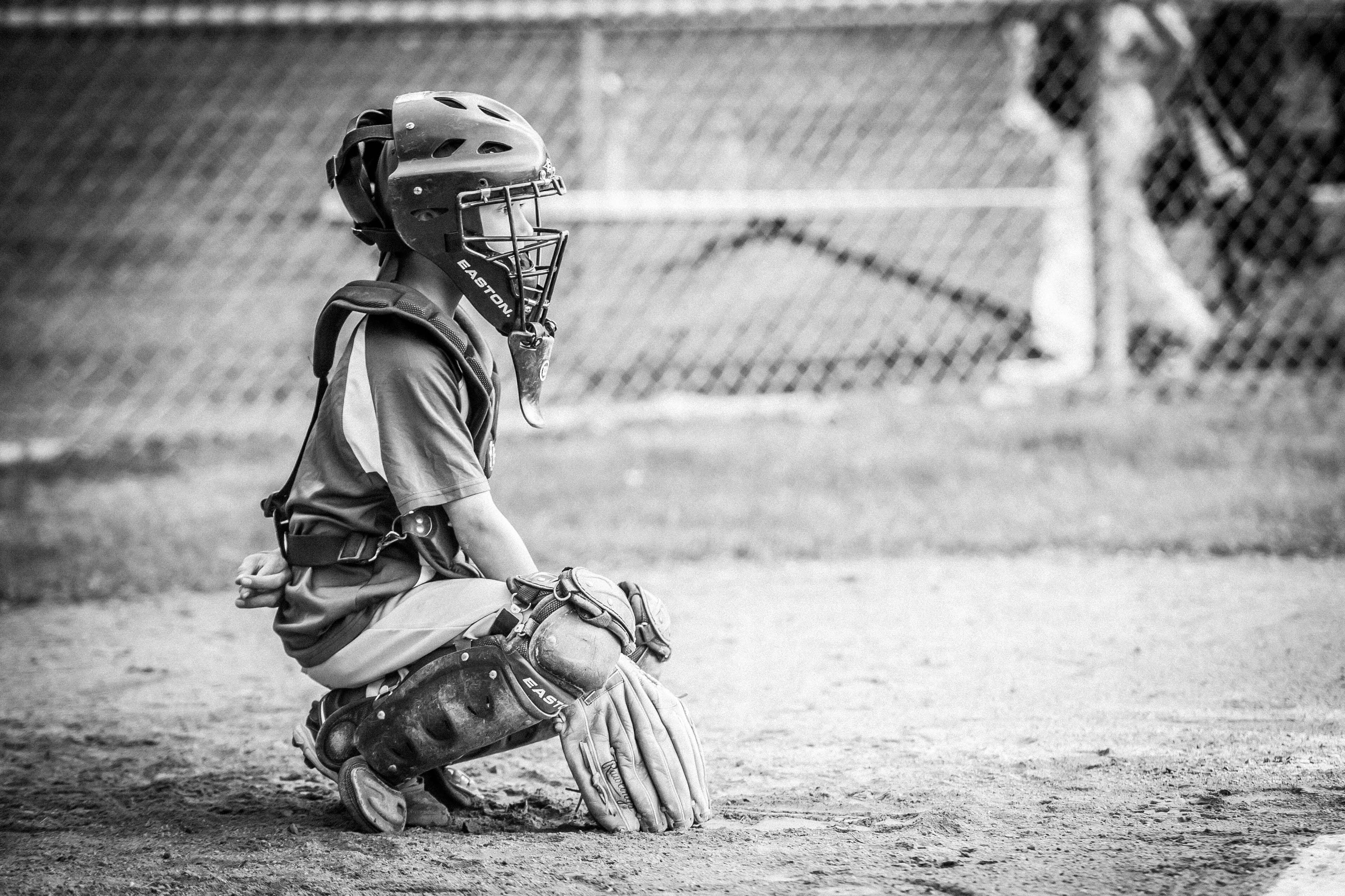 Black and white image of a young white boy in catchers gear waiting for a pitch.