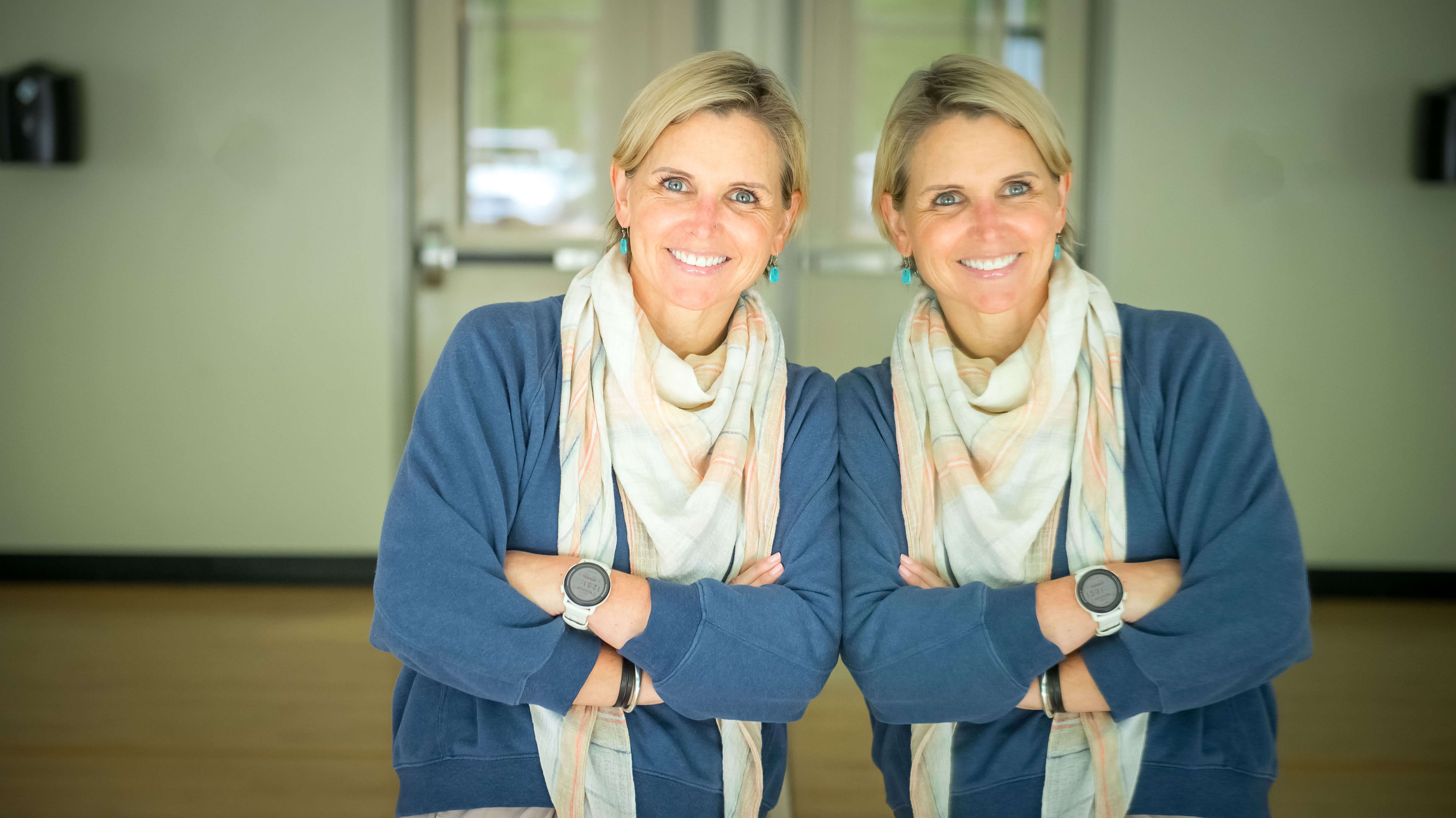 Color image of a white blonde 50 yo women standing beside a mirror.